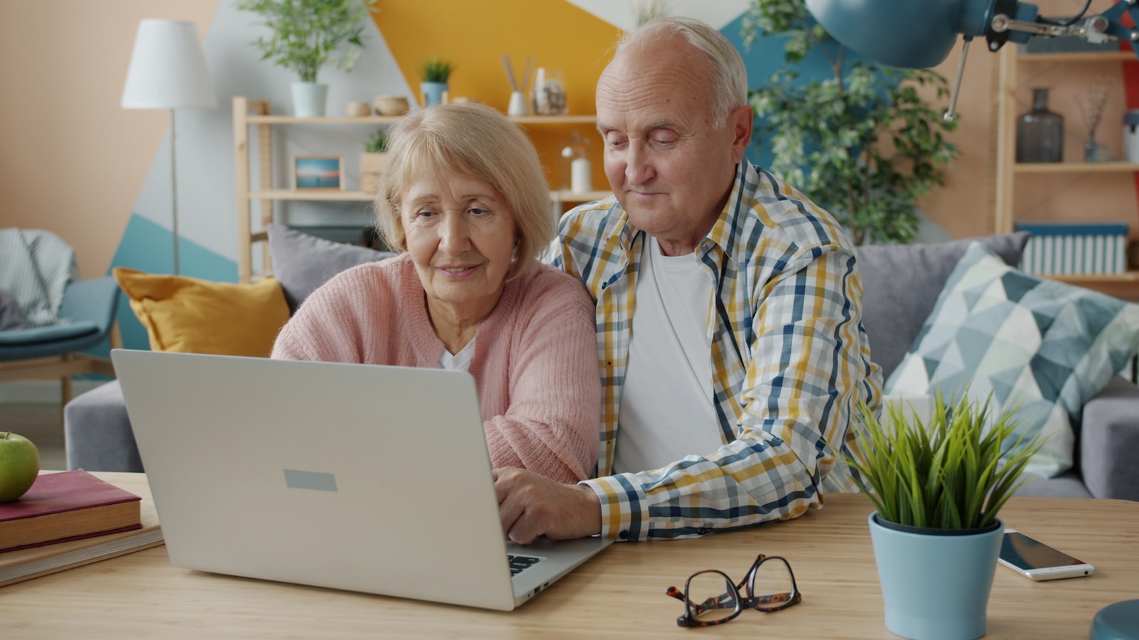 Smiling older couple at home looking at a laptop together
